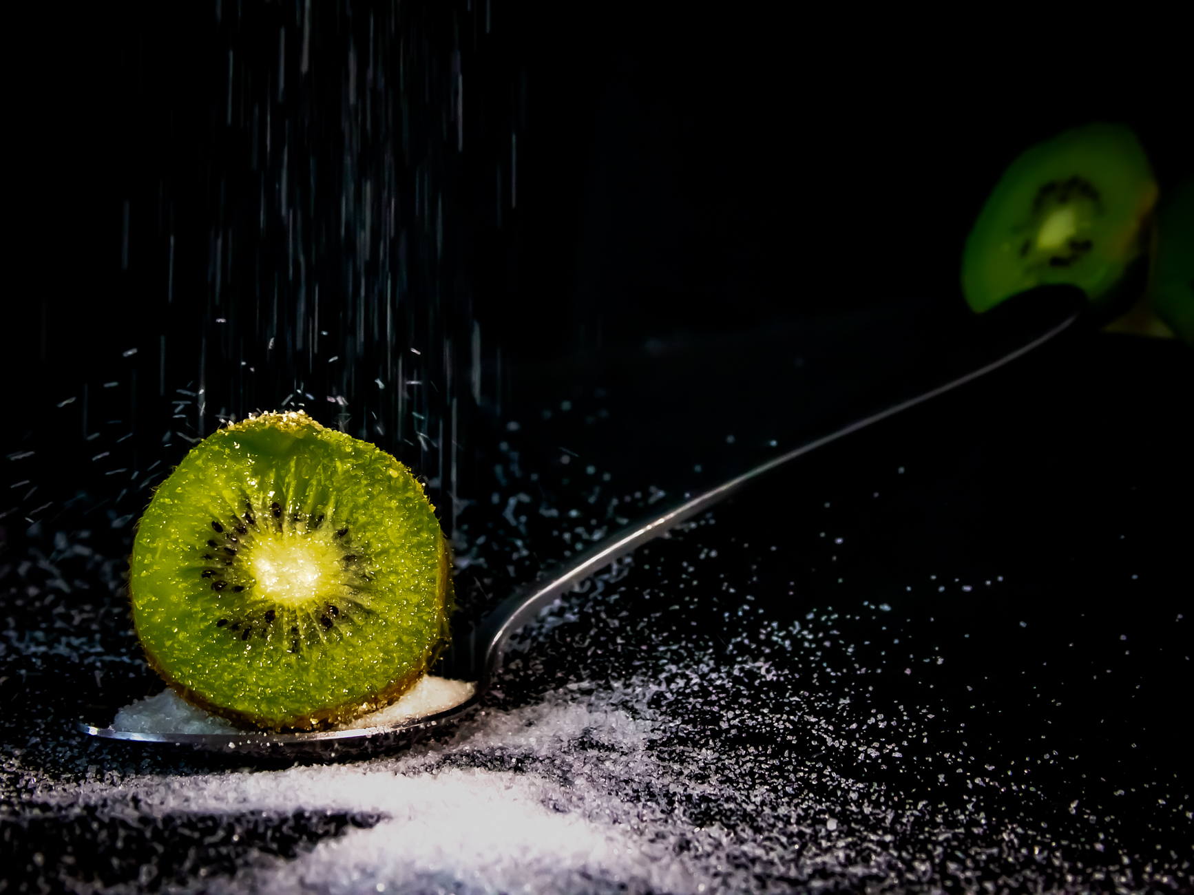 Sugar falling on slice of kiwi